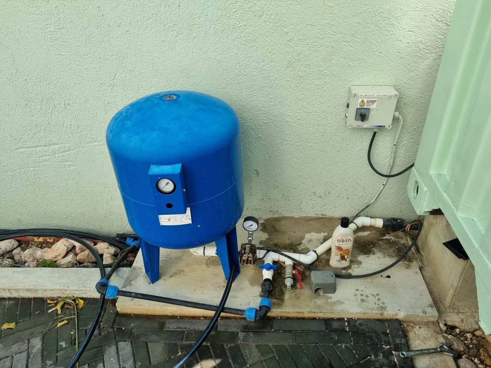 Tanque de presión de agua azul con tubería de PVC expuesta antes de la instalación